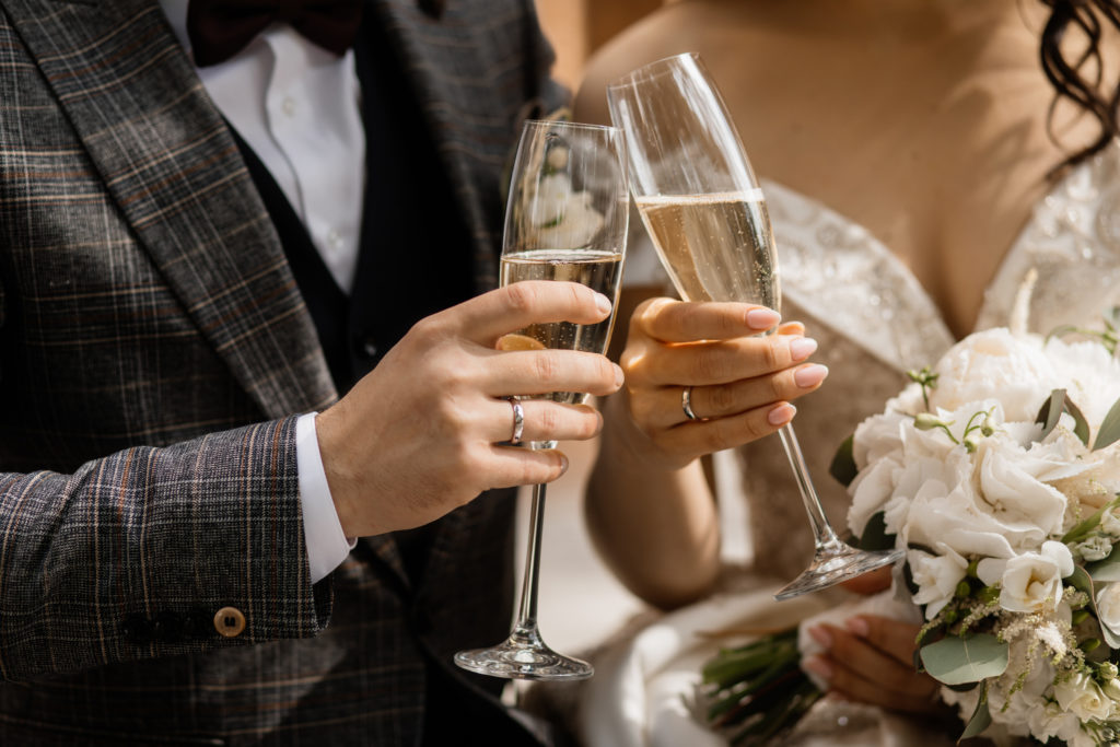 Front view of wedding couple's hands with champagne glasses and